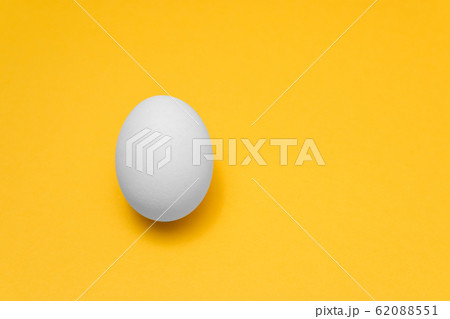 one white egg on yellow background on left side for designs, visual art for easter advertise 62088551