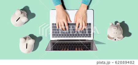 Person using laptop with three piggy banks 62089482