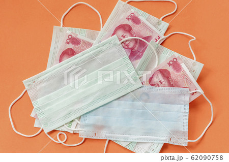 Disposable protective masks and cash chinese money on orange background. Concept of medicines deficiency, personal protection, outbreak of dangerous coronovirus 62090758