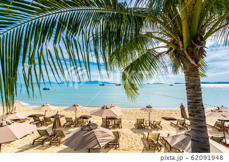 Beautiful tropical beach sea and ocean with coconut palm tree and umbrella and chair on blue sky and white cloud Beautiful tropical beach sea and ocean with coconut palm tree and umbrella and chair on blue sky and white cloud 62091948