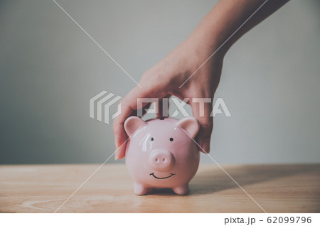 Man hand holding piggy bank on wood table. Save money and financial investment Man hand holding piggy bank on wood table. Save money and financial investment 62099796