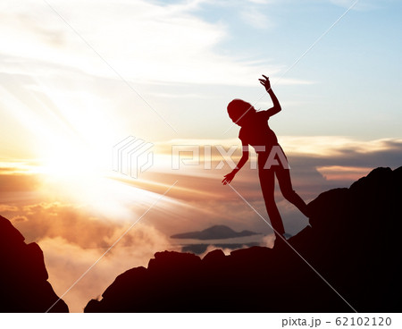 Black silhouette of woman walking down of rock. 62102120