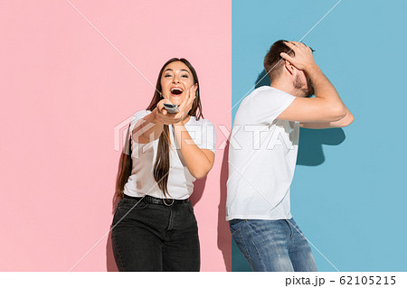 Young emotional man and woman on pink and blue background Young emotional man and woman on pink and blue background 62105215