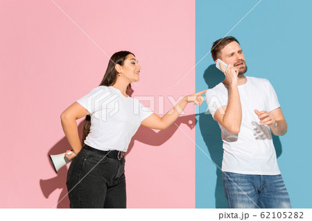 Young emotional man and woman on pink and blue background Young emotional man and woman on pink and blue background 62105282