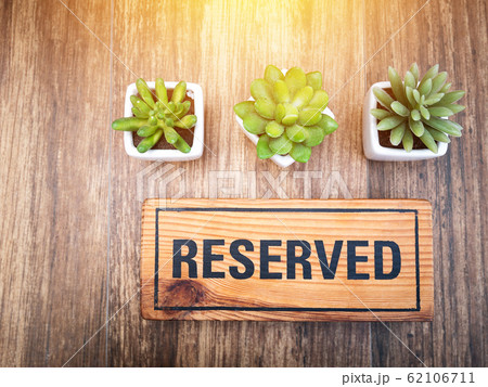 Wooden reserved sign on top of a wooden table in a restaurant, Reservation seat at restaurant for dating on celebrate day concept. Reserved sign from top view decorate with little cactus and light 62106711