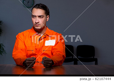 Young convict man sitting in dark room 62107444