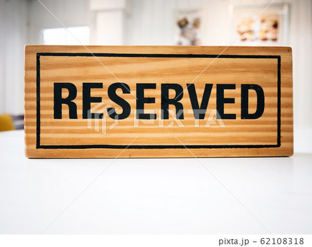Reservation seat at restaurant for dating on celebrate day concept. Restaurant with reserved wooden sign on white table with cafe decorate places setting and evening light with bokeh for dinner time 62108318