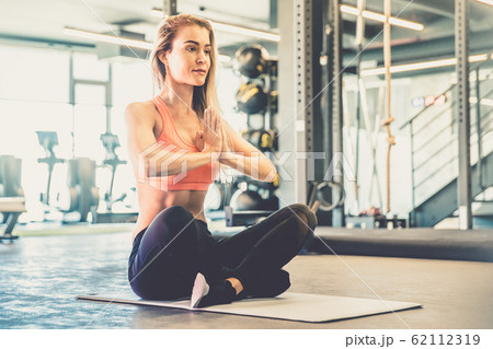 young woman practicing yoga on mat in gym 62112319