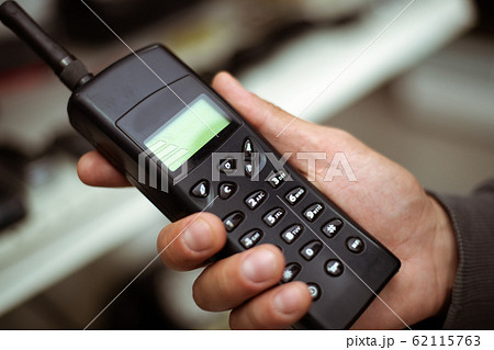 Male hand holds a black plastic vintage cell or 62115763