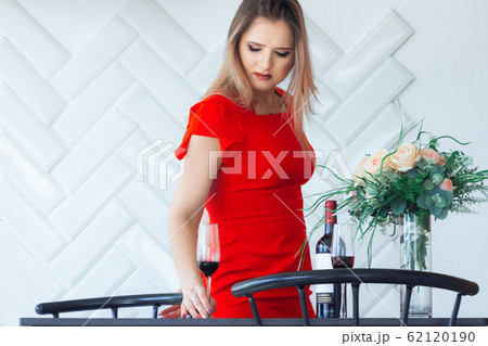 Young elegant beautiful girl picks from the table in the kitchen a glass of wine Young elegant beautiful girl picks from the table in the kitchen a glass of wine 62120190