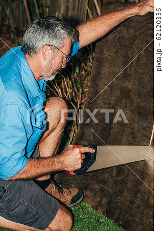 A man sawing a plank in the garden. Seasonal gardening. Repair work 62120336