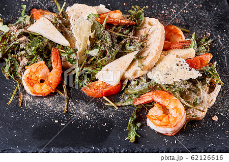 Delicious dish with grilled shrimps, squid, croutons and arugula salad and spicy fried prawns. Restaurant menu, natural and organic food concept. Delicious dish with grilled shrimps, squid, croutons and arugula salad and spicy fried prawns. Restaurant menu, natural and organic food concept. 62126616