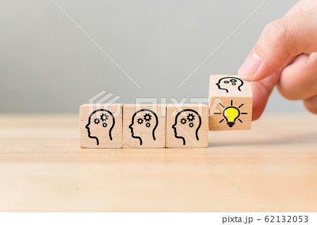 Hand flip over wooden cube block with head human symbol and light bulb icon Hand flip over wooden cube block with head human symbol and light bulb icon 62132053