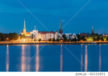 Riga, Latvia. Panoramic Picturesque Urban View Of Daugava Or Western Dvina River In Central Part Of City With Famous Landmarks In Bright Illumination Under Blue Sky In Summer Night 62133951