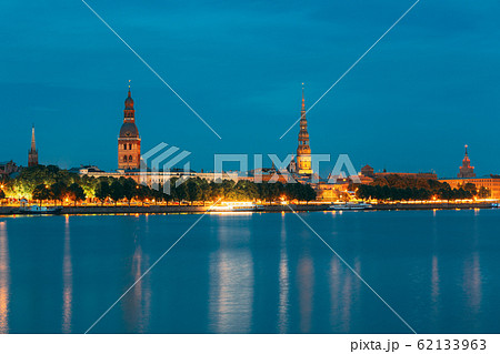 Riga, Latvia. Panoramic Picturesque Urban View Of Daugava Or Western Dvina River In Central Part Of City With Famous Landmarks In Bright Illumination Under Blue Sky In Summer Night Riga, Latvia. Panoramic Picturesque Urban View Of Daugava Or Western Dvina River In Central Part Of City With Famous Landmarks In Bright Illumination Under Blue Sky In Summer Night 62133963