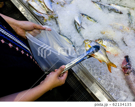 Woman hand using tongs picking fish at seafood supermarket 62134135