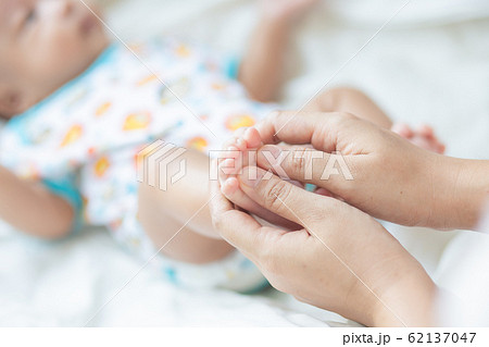 Baby boy foot massage by mom on white blanket 62137047