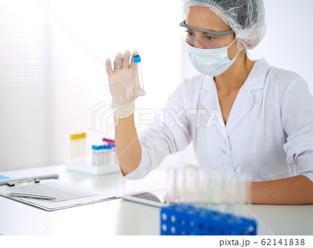 Professional female scientist in protective eyeglasses researching tube with reagents in laboratory. Concepts of medicine and research 62141838