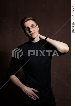 Man in round glasses and a black shirt. 62142242