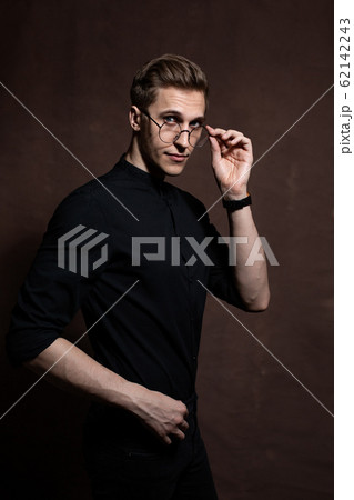 Man in round glasses and a black shirt. 62142243