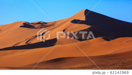 Beautiful landscape with red huge sand dunes at sunset in desert. Sossusvlei, Namib Naukluft National Park, Namibia. Stunning natural geometry without people 62142969