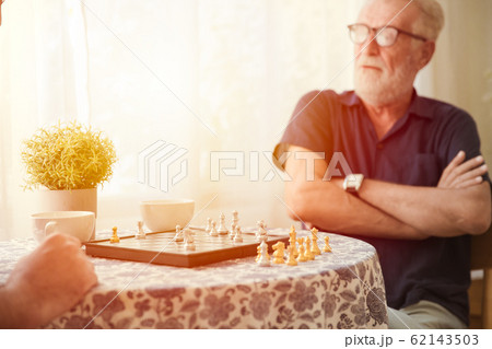 Smart elder with chess board game play at home 62143503