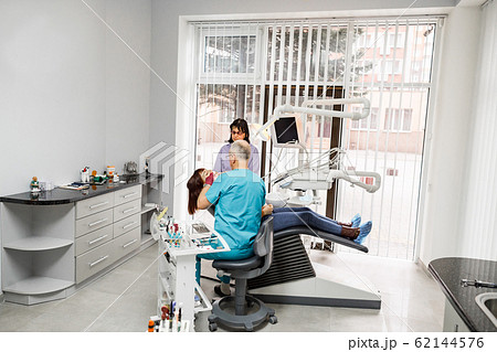 A team of Caucasian dentists with young female client in a dental office. Oral care, healthy teeth, stomatology concept 62144576