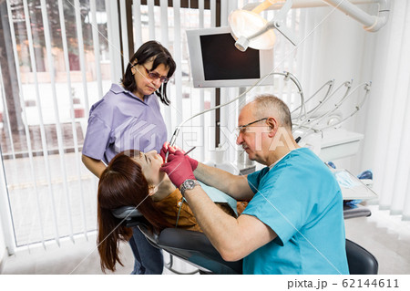 Senior male dentist doctor and his female nurse treats a patient. Dentistry and healthcare, oral care concept 62144611