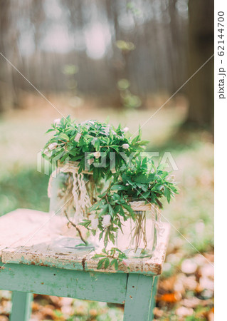 Bouquet of white spring flowers in Glass Jar On wooden chair in the forest outdoors Bouquet of white spring flowers in Glass Jar On wooden chair in the forest outdoors 62144700