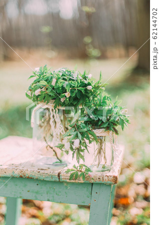 Bouquet of white spring flowers in Glass Jar On wooden chair in the forest outdoors Bouquet of white spring flowers in Glass Jar On wooden chair in the forest outdoors 62144702