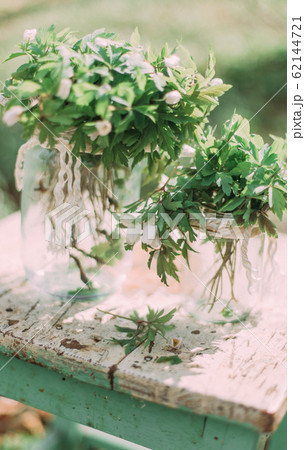 Bouquet of white spring flowers in Glass Jar On wooden chair in the forest outdoors Bouquet of white spring flowers in Glass Jar On wooden chair in the forest outdoors 62144721