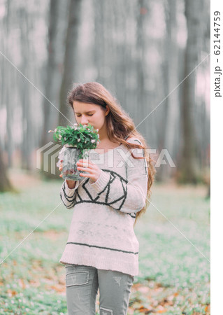 beautiful young girl woman walking through the green forest in spring, holding glass ar with white spring flowers beautiful young girl woman walking through the green forest in spring, holding glass ar with white spring flowers 62144759
