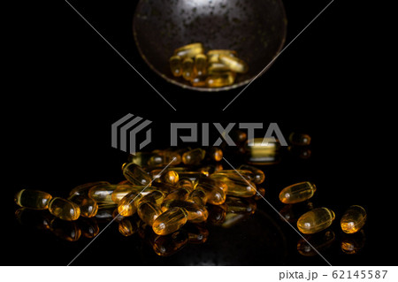 Golden fish oil isolated on black glass 62145587