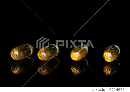 Golden fish oil isolated on black glass 62146024