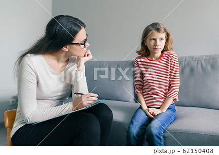 Professional child psychologist talking with child girl in office Professional child psychologist talking with child girl in office 62150408