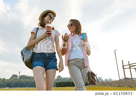 Mother daughter walking on the lawn in the park, The relationship between parent and child teenager, sunny summer day 62150655