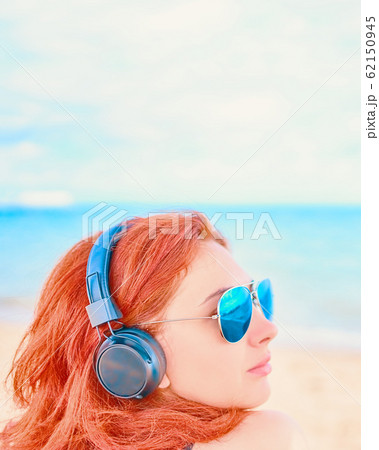 Beautiful woman in sunglasses listening to music on the beach. Beautiful woman in sunglasses listening to music on the beach. 62150945