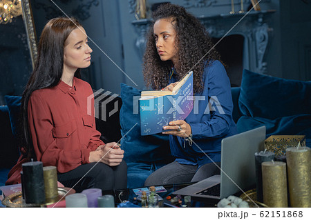 Young serious soothsayer staring at her client Young serious soothsayer staring at her client 62151868