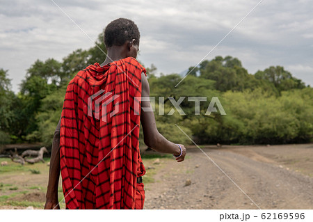 Maasai man in red traditional cloth walking near Lake Natron and Lengai volcano, Tanzania 62169596