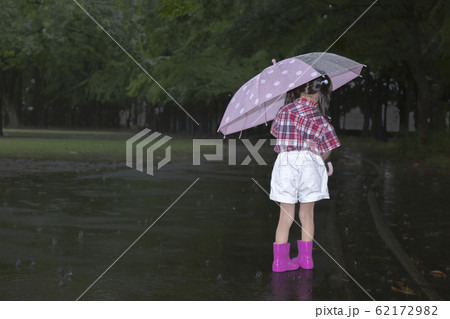 雨降りの暗い林を傘を差して歩く幼い女の子。孤独、虐待、一人ぼっちイメージ 62172982