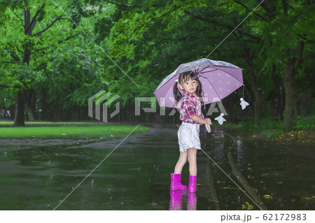 雨降りの暗い林を傘を差し笑顔で振り返る幼い女の子。 雨降りの暗い林を傘を差し笑顔で振り返る幼い女の子。 62172983
