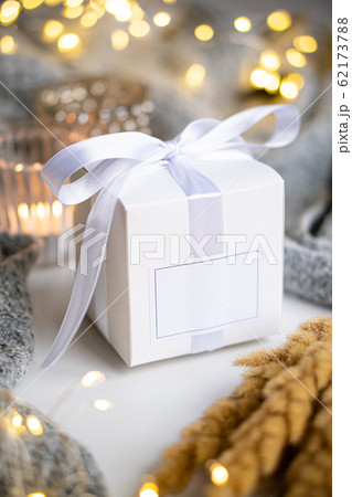 Holiday white gift box with satin ribbon and empty label with interior objects and accessories Holiday white gift box with satin ribbon and empty label with interior objects and accessories 62173788