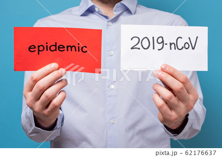 Caucasian man holding a red banner with a word epidemic and white banner 2019-nCoV on blue background. Caucasian man holding a red banner with a word epidemic and white banner 2019-nCoV on blue background. 62176637