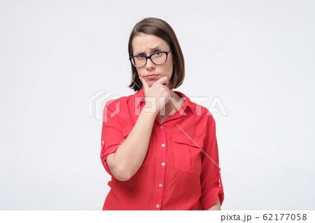 Pretty brunette woman with glasses frowning her eyebrow while looking aside 62177058