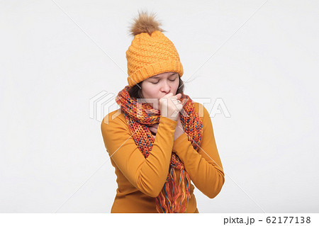 Sick caucasian woman in scarf and hat coughing being ill with grippe. 62177138