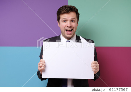 Young caucasian businessman in business outfit holding at blank canvas Young caucasian businessman in business outfit holding at blank canvas 62177567