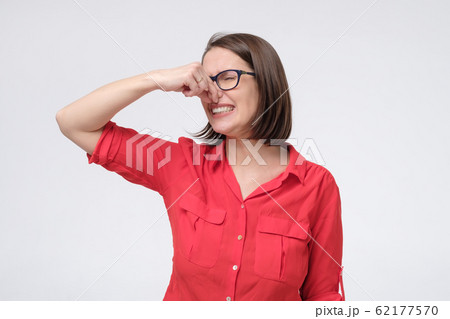 Mature caucasian man in glasses and red shirt plugs close nose with fingers feels unpleasant scent Mature caucasian man in glasses and red shirt plugs close nose with fingers feels unpleasant scent 62177570