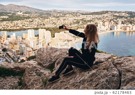Woman seated on stone rock posing makes selfie 62178463
