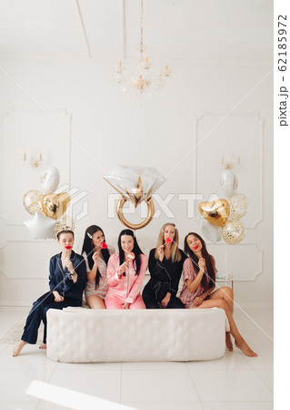 Happy pretty female friends sitting on the edge of 62185972