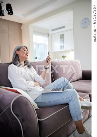Smiling adult lady sending messages to friends stock photo Smiling adult lady sending messages to friends stock photo 62187567